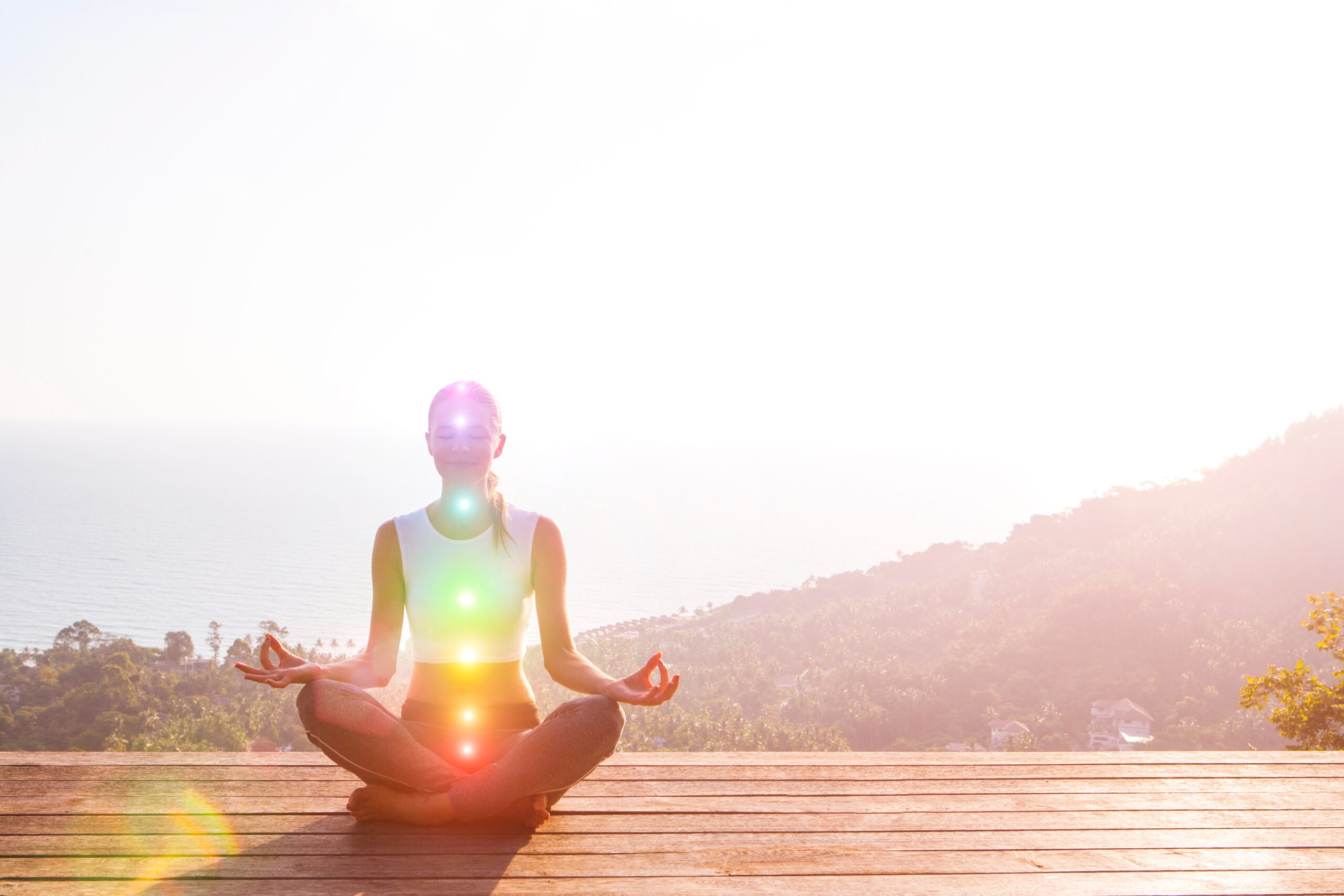 Beautiful Woman Sits In A Pose Of A Half Lotus On High Place Amazing View Of The Island Outside, She Practicing Yoga Meditation Glowing Seven All Chakra Eyes Closed Calm.